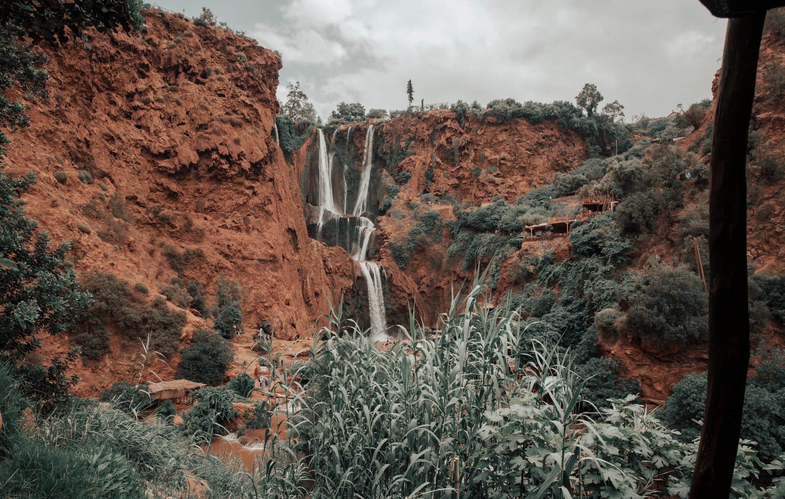 The Ouzoud waterfalls dropping down a red, green-draped cliff